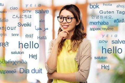 translation, education and people concept - happy asian woman in glasses or student over greeting words in different foreign languages